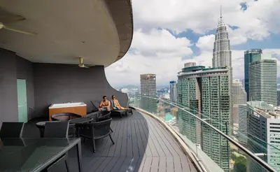 two people sitting on the edge of a balcony of a building at The Penthouse KLCC in Kuala Lumpur