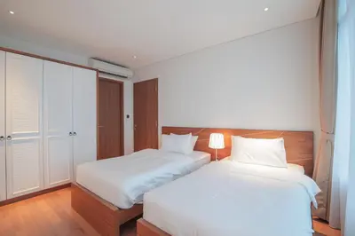 two beds in a bedroom with white sheets at The Penthouse KLCC in Kuala Lumpur