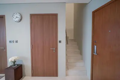 a hallway with a wooden door and stairs with a clock at The Penthouse KLCC in Kuala Lumpur