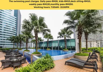 a swimming pool in a building with palm trees and benches at Vortex KLCC Apartments in Kuala Lumpur