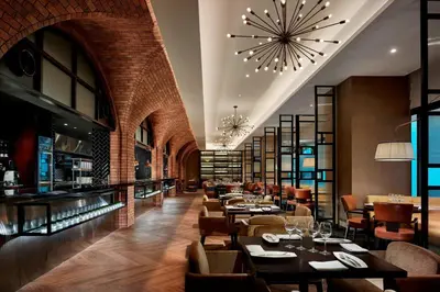 a restaurant with tables and chairs and a bar at Hotel Stripes Kuala Lumpur, Autograph Collection in Kuala Lumpur