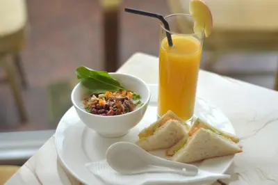 a plate of food with a bowl of salad and a glass of orange juice at InnB Park Hotel in Kuala Lumpur