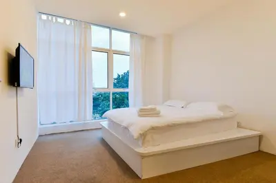 a white bedroom with a bed and a large window at Fumah Hotel Jalan Kuching in Kuala Lumpur