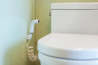 a white toilet in a bathroom with a hose at Soho Suites KLCC by Leala in Kuala Lumpur