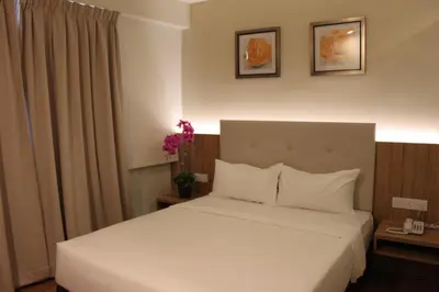 a hotel room with a bed with white sheets at BIG M Hotel in Kuala Lumpur
