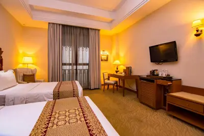 a hotel room with two beds and a desk and a television at Royale Chulan Kuala Lumpur in Kuala Lumpur