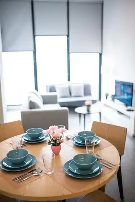 a wooden table with plates and utensils on it at KL Sentral Bangsar Suites EST BY PSM LUXURY SUITES in Kuala Lumpur