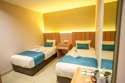 a hotel room with two beds and a table at Alaxis Hotel in Kuala Lumpur