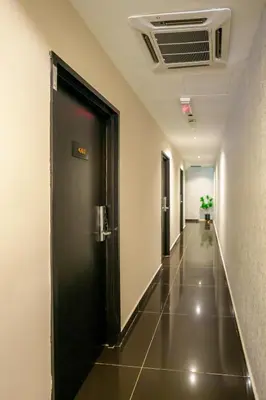 a hallway with a black door and a tile floor at Alaxis Hotel in Kuala Lumpur