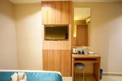 a room with a bed and a desk and a tv at Alaxis Hotel in Kuala Lumpur