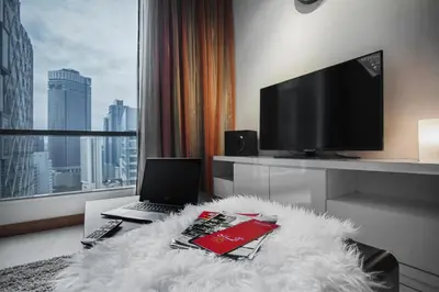 a living room with a laptop and a white rug at Soho Suites KLCC by 21 Century travel in Kuala Lumpur