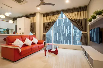 a living room with a red couch and a large window at Soho Suites KLCC by 21 Century travel in Kuala Lumpur