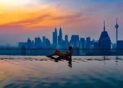 a woman laying in a infinity pool with a city skyline at Suites & Residences @ Regalia by PLC in Kuala Lumpur