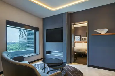 a living room with a tv and a bedroom at Le Méridien Kuala Lumpur in Kuala Lumpur