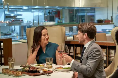 a man and woman sitting at a table with a glass of wine at Le Méridien Kuala Lumpur in Kuala Lumpur
