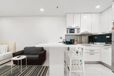 a white kitchen with a couch and a table at Summer Suites KLCC Apartments by soulasia in Kuala Lumpur