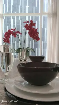 a table with two bowls and vases with red flowers at Soho Suites KLCC by LX Suites 2 in Kuala Lumpur