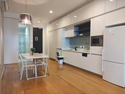 a kitchen with a table and a white refrigerator at KL Platinum KLCC By Hive KL in Kuala Lumpur