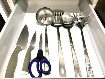 a drawer with some spoons forks and a pair of scissors at KL Gateway Residency in Kuala Lumpur