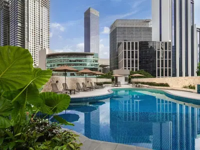 a swimming pool with chairs and buildings in the background at Novotel Kuala Lumpur City Centre in Kuala Lumpur
