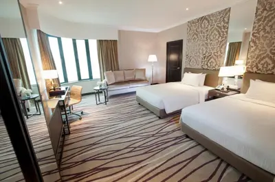 a hotel room with two beds and a couch at Dorsett Kuala Lumpur in Kuala Lumpur