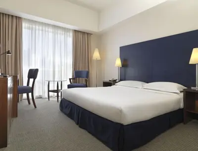 a hotel room with a large bed and a table and chairs at Hotel Capitol Kuala Lumpur in Kuala Lumpur