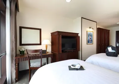 a hotel room with two beds and a desk with a television at Berjaya Times Square Hotel, Kuala Lumpur in Kuala Lumpur