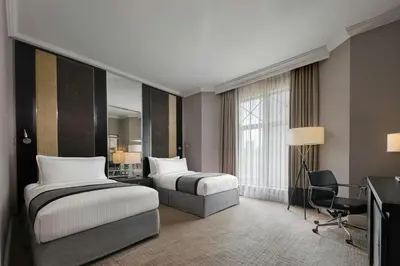 a hotel room with two beds and a desk at The Ritz-Carlton, Kuala Lumpur in Kuala Lumpur