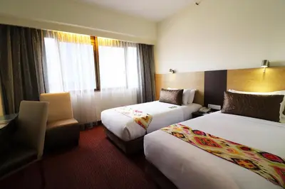 a hotel room with two beds and a chair at Hotel Grand Continental Kuala Lumpur in Kuala Lumpur
