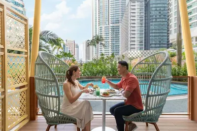a man and woman sitting at a table on a balcony at Renaissance Kuala Lumpur Hotel & Convention Centre in Kuala Lumpur