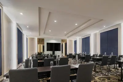 a conference room with tables and chairs and a screen at AC Hotel by Marriott Kuala Lumpur in Kuala Lumpur