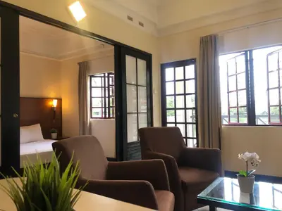 a hotel room with a bed and chairs and windows at Flamingo Hotel By The Lake, Kuala Lumpur in Kuala Lumpur