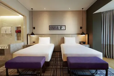 two beds in a hotel room with purple seats at Hilton Kuala Lumpur in Kuala Lumpur