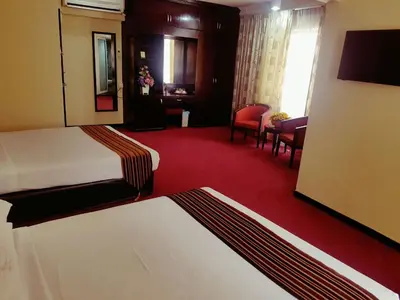 a hotel room with a bedroom with a bed and chairs at Palace Hotel in Kuala Lumpur