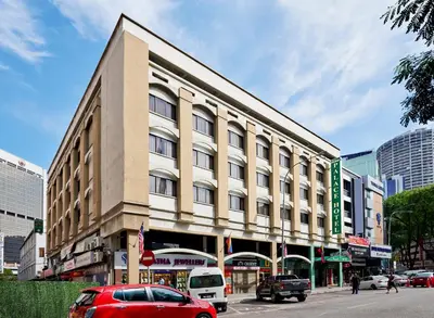 a building on a street with cars parked in front of it at Palace Hotel in Kuala Lumpur
