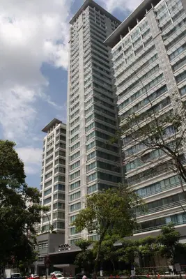 a large tall building with trees in front of it at PARKROYAL Serviced Suites Kuala Lumpur in Kuala Lumpur