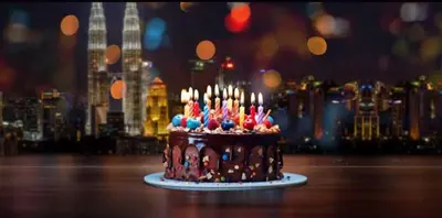a chocolate cake with lit candles on a table at Hilton Garden Inn Kuala Lumpur - North in Kuala Lumpur