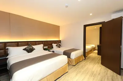 a hotel room with two beds and a mirror at M&M Hotel in Kuala Lumpur