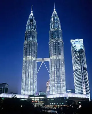 three tall skyscrapers in a city at night at Soho Suites KLCC by LX Suites in Kuala Lumpur