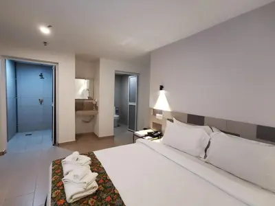 a bedroom with a large white bed and a bathroom at Leo Palace Hotel New Wing, WTC Kuala Lumpur in Kuala Lumpur