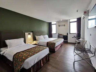 a hotel room with two beds and a green wall at Leo Palace Hotel New Wing, WTC Kuala Lumpur in Kuala Lumpur