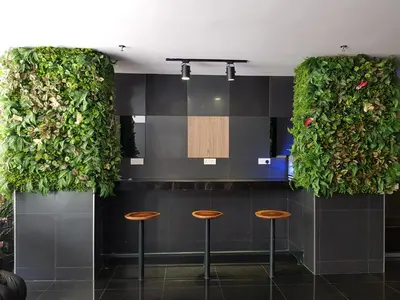 a bar with three stools and plants on the wall at Leo Palace Hotel New Wing, WTC Kuala Lumpur in Kuala Lumpur