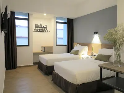 a hotel room with two beds and a table at Leo Palace Hotel New Wing, WTC Kuala Lumpur in Kuala Lumpur