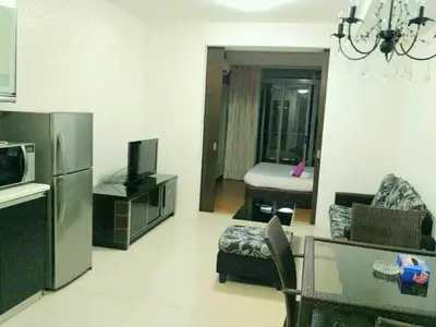 a living room with a couch and a kitchen with a refrigerator at Taragon Putrie Bintang suites in Kuala Lumpur