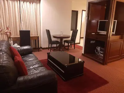 a living room with a leather couch and a table at Genius Service Suites at time square kl in Kuala Lumpur