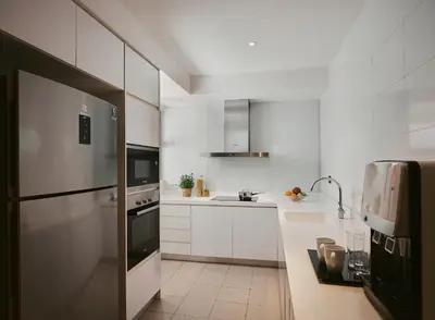 a kitchen with white cabinets and a stainless steel refrigerator at TRILLION SUITES by SLG in Kuala Lumpur