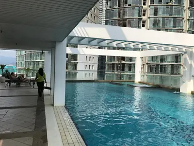 a woman walks past a swimming pool in a building at Parkview KLCC in Kuala Lumpur