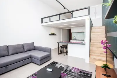 a living room with a couch and a kitchen at The Establishment KL Sentral Bangsar by Plush in Kuala Lumpur