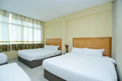 two beds in a hotel room with white sheets at Hotel Raja Bot in Kuala Lumpur
