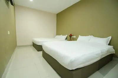 two beds in a hotel room with white sheets at Hotel Raja Bot in Kuala Lumpur